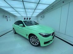 a green car is parked in a white room