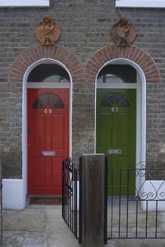 two red and green doors in front of a brick building