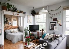 a living room filled with furniture and lots of plants on top of the windowsill