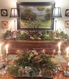 a christmas table with candles and decorations on the top, in front of a painting