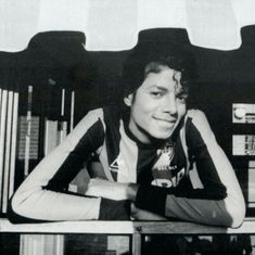 a black and white photo of a man sitting at a table with his arms crossed