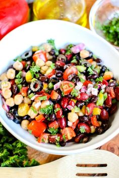 a white bowl filled with black beans and veggies on top of a wooden cutting board