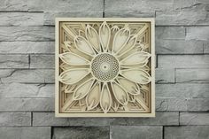 an intricately designed paper art piece on a stone wall with a flower in the center