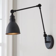 an industrial style wall light with a black metal arm and white walls in the background