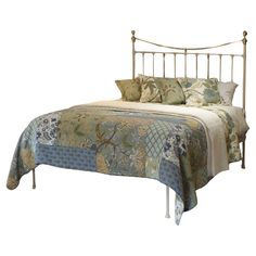 a bed with a metal headboard and foot board, made up in floral fabric