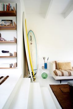 a surfboard leaning against the wall in a living room with other furniture and decor