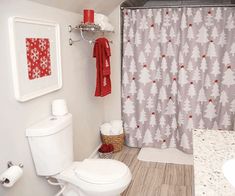 a white toilet sitting in a bathroom next to a shower curtain with christmas decorations on it