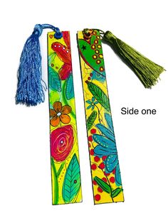 two colorful bookmarks with tassels on each one and the words side one