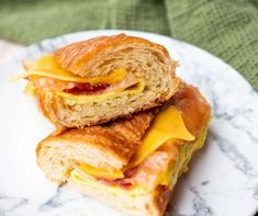 two croissants with cheese and bacon are on a marbled white plate