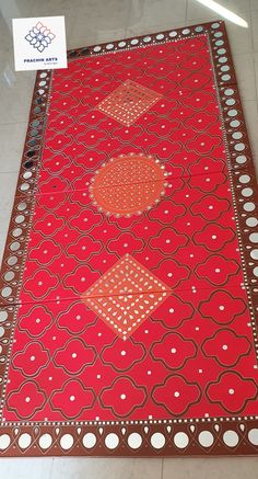 a red rug with white dots and circles on it in the middle of a tile floor