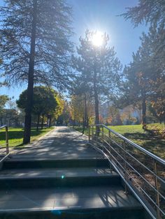 the sun shines brightly through the trees over some steps that lead to a park