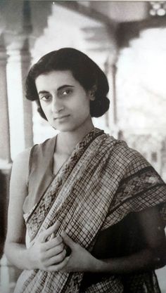 an old black and white photo of a woman in a sari with her hands on her chest