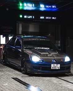 a black car parked in front of a building with lights on it's sides