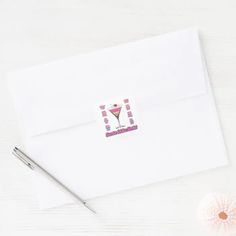 a white envelope with a pink martini sticker on it and a pen next to it