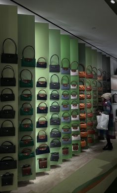 there are many purses on display in the store and one person is looking at them