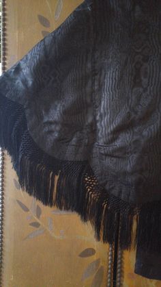 "One of a kind amazing Victorian black brocade embroidered fringed cape! This awesome cape has embroidered collars and across shoulders and front, the embroidery is a light black/ brown colour. There is a large black ribbon band that comes around the back of neck and down front sides with ribbon flowers at the ends and ties up the front, the ribbon is torn in places, could be easily replaced if you have a good seamstress! The black crochet and fringing is amazing! There are metal hook and eye fa