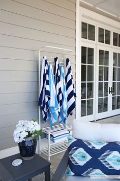 towels are hanging on a rack in front of a patio area with furniture and flowers