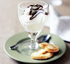 an ice cream sundae with chocolate sauce and whipped cream in a glass on a plate