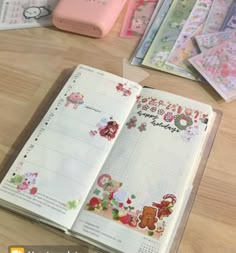 an open planner book sitting on top of a wooden table next to other stationery items