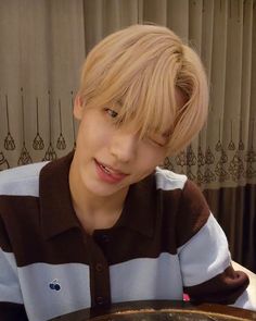 a young man with blonde hair sitting at a table