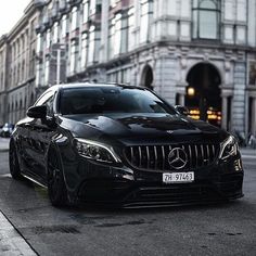 a black car parked in front of a tall building