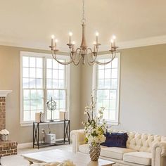 a living room filled with furniture and a chandelier hanging from the ceiling over a fire place