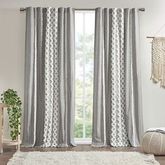 a living room with a white rug and gray curtains in front of a window that is open