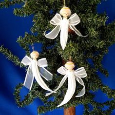 an ornament hanging from a tree decorated with white ribbon and angel ornaments on it