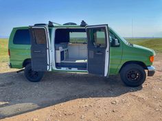 a green van with its doors open sitting in the dirt