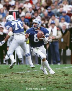 a football player running with the ball in his hand while people watch from the stands