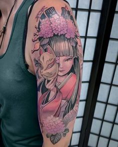 a woman with a tattoo on her arm holding a cat and flowers in her hair