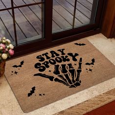 a door mat with the words stay spooky on it next to a potted plant