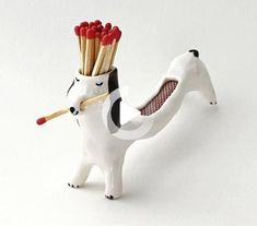 a dog with matches sticking out of it's mouth and holding something in its mouth