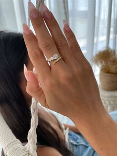 a woman is holding her hand up to the camera and wearing a ring with a diamond on it