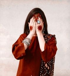 a woman covering her face with both hands while wearing red and white polka dot designs