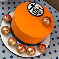 an orange cake with gold and red decorations sits on a white plate next to blue polka dot tablecloth