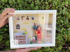 a person holding up a miniature photo in front of a wall with pictures on it