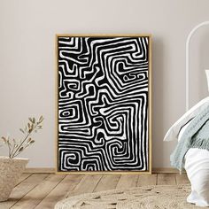 a white bed sitting next to a black and white art piece on top of a wooden floor