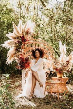 a woman is sitting on a chair in the woods holding an umbrella with pamodia flowers