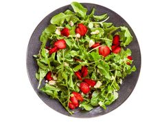 a salad with strawberries in a black bowl