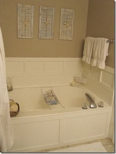 a white bath tub sitting next to a bathroom sink under two pictures on the wall