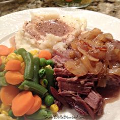 a white plate topped with meat and veggies next to mashed potatoes on top of a counter