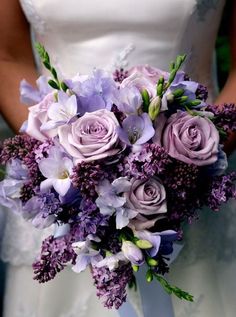 the bride's bouquet has purple flowers and lavenders on it, along with greenery