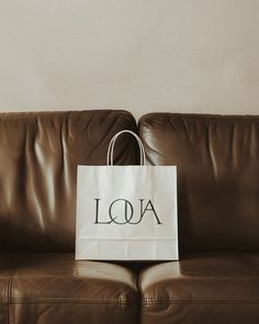 a white bag sitting on top of a brown leather couch with the word aoa printed on it