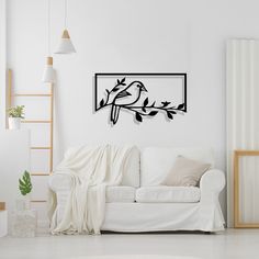 a living room with a white couch and black birds on the tree branch wall decal