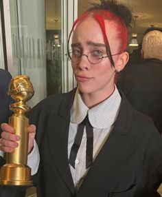 a woman with red hair holding up a golden trophy