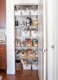 an organized pantry with white bins and baskets