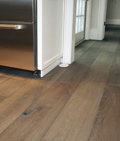 a kitchen with wood flooring and stainless steel refrigerator freezer next to an open door