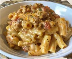 a white plate topped with pasta covered in cheese and meat sauce on top of a marble counter