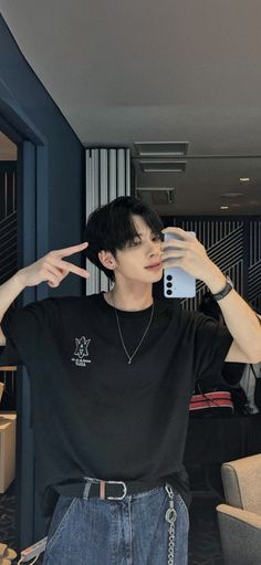 a man taking a selfie with his cell phone in front of him and wearing a black t - shirt